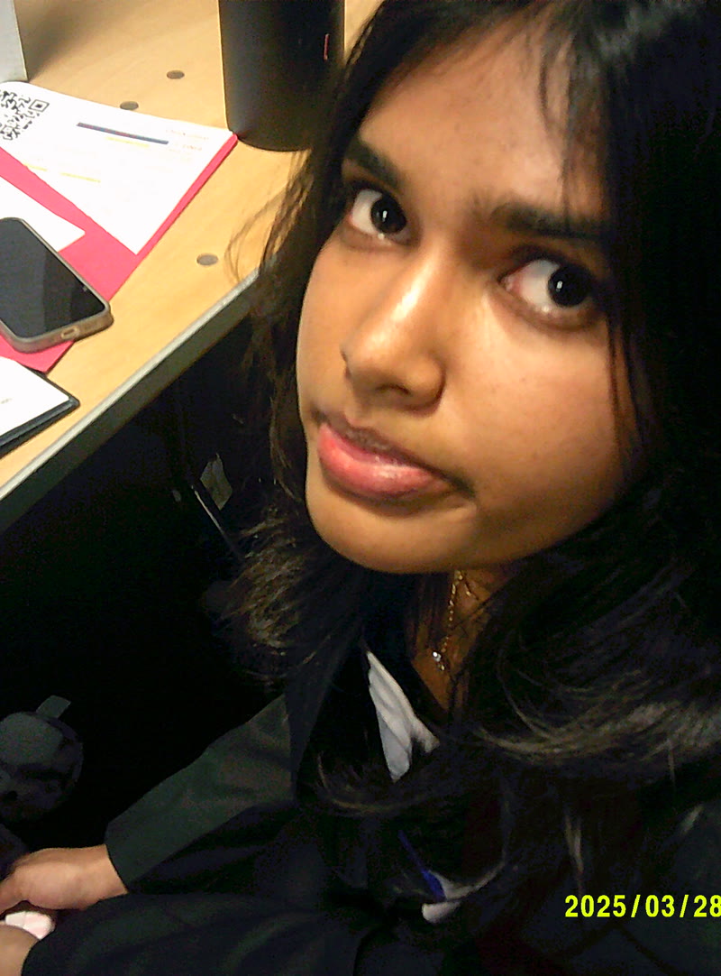 Shruthika Omkumar at a desk, looking up at the camera