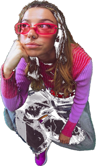 Shruthika Omkumar in a pink striped sweater and pink sunglasses, crouched with her chin in her hand